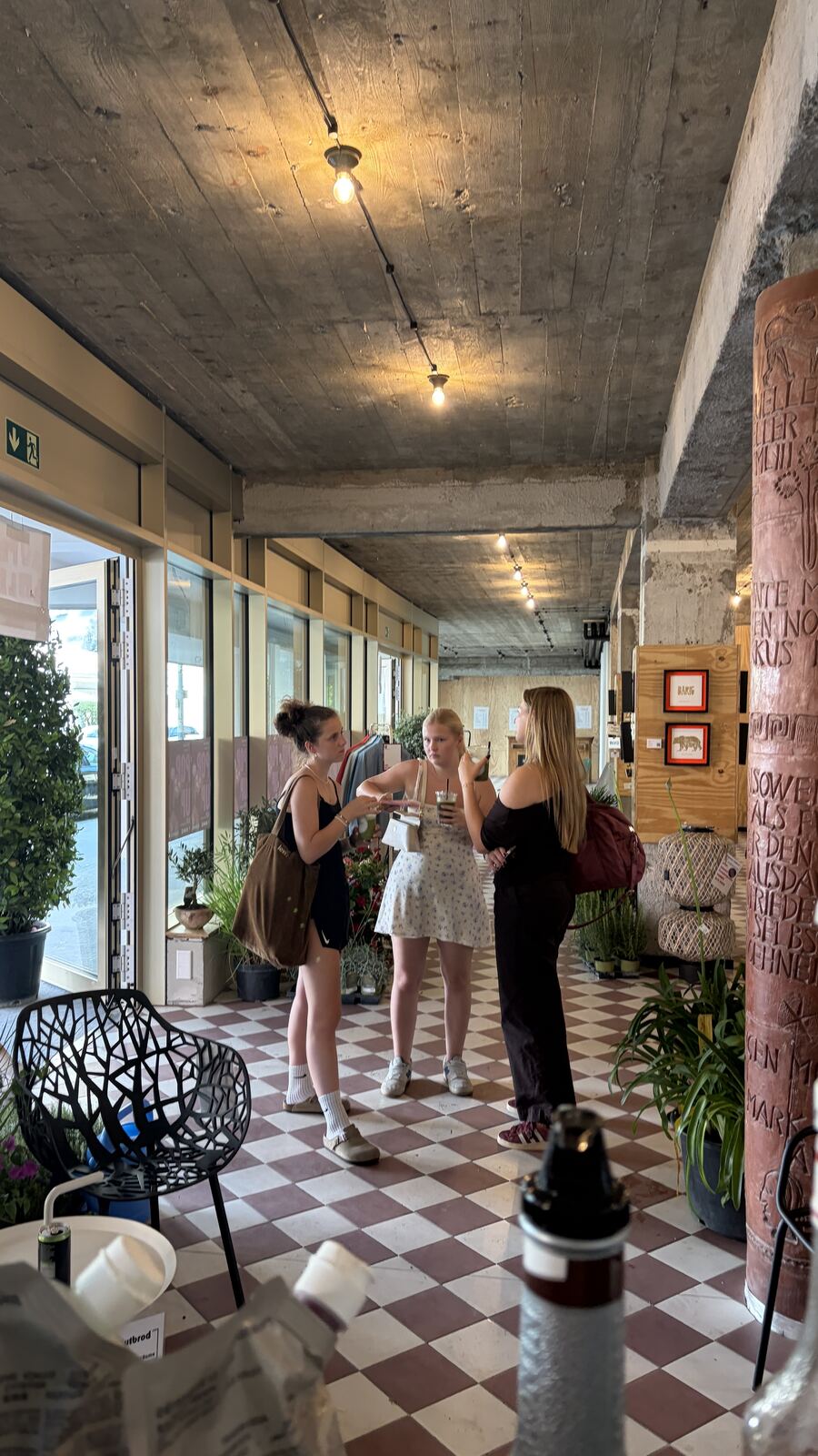 Gäste stöbern am Kleiderständer im Pop-up, im Hintergrund die Matcha-Bar
